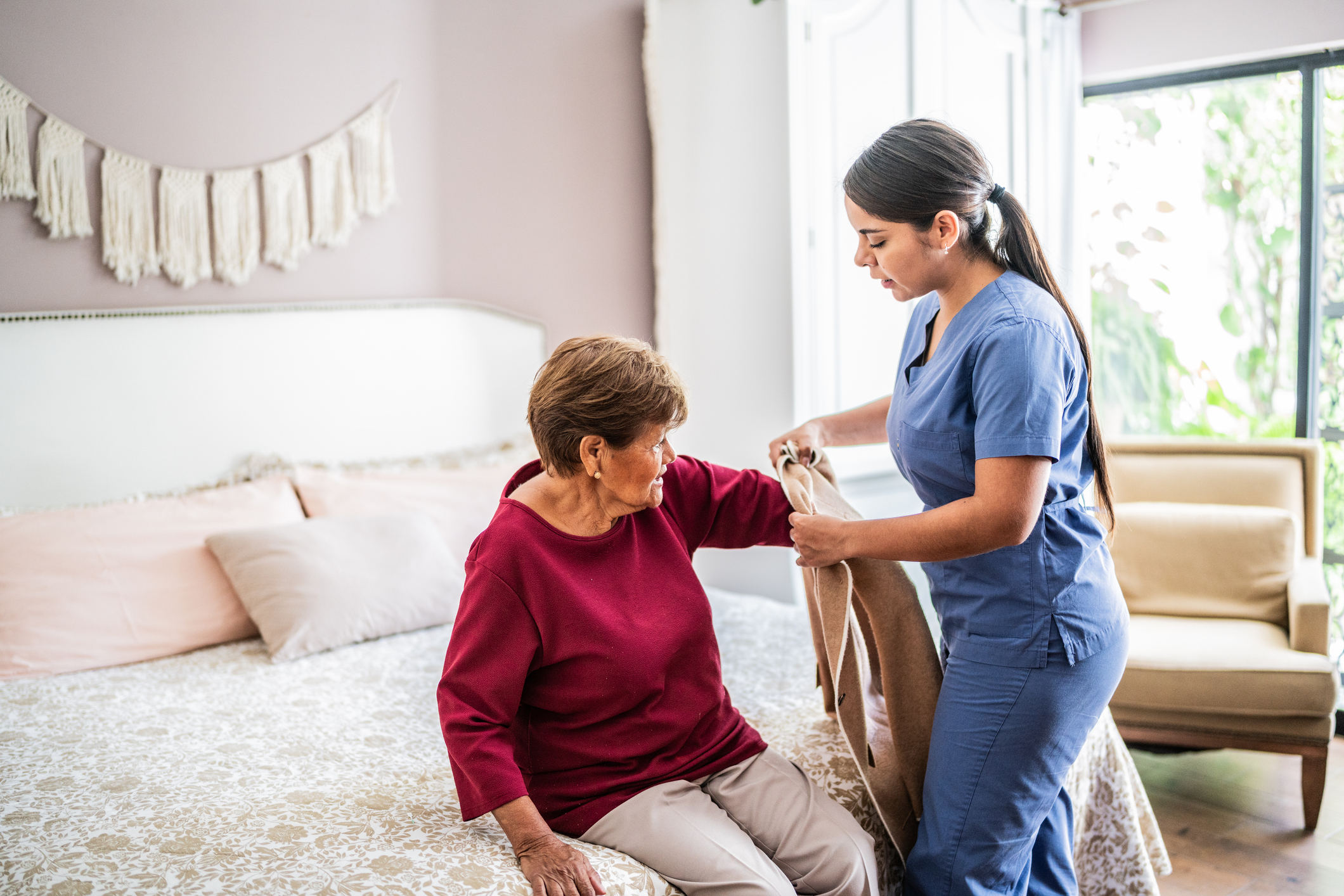 Home caregiver assisting a senior woman to get clothed in a nursing home Home caregiver assisting a senior woman to get clothed in a nursing home