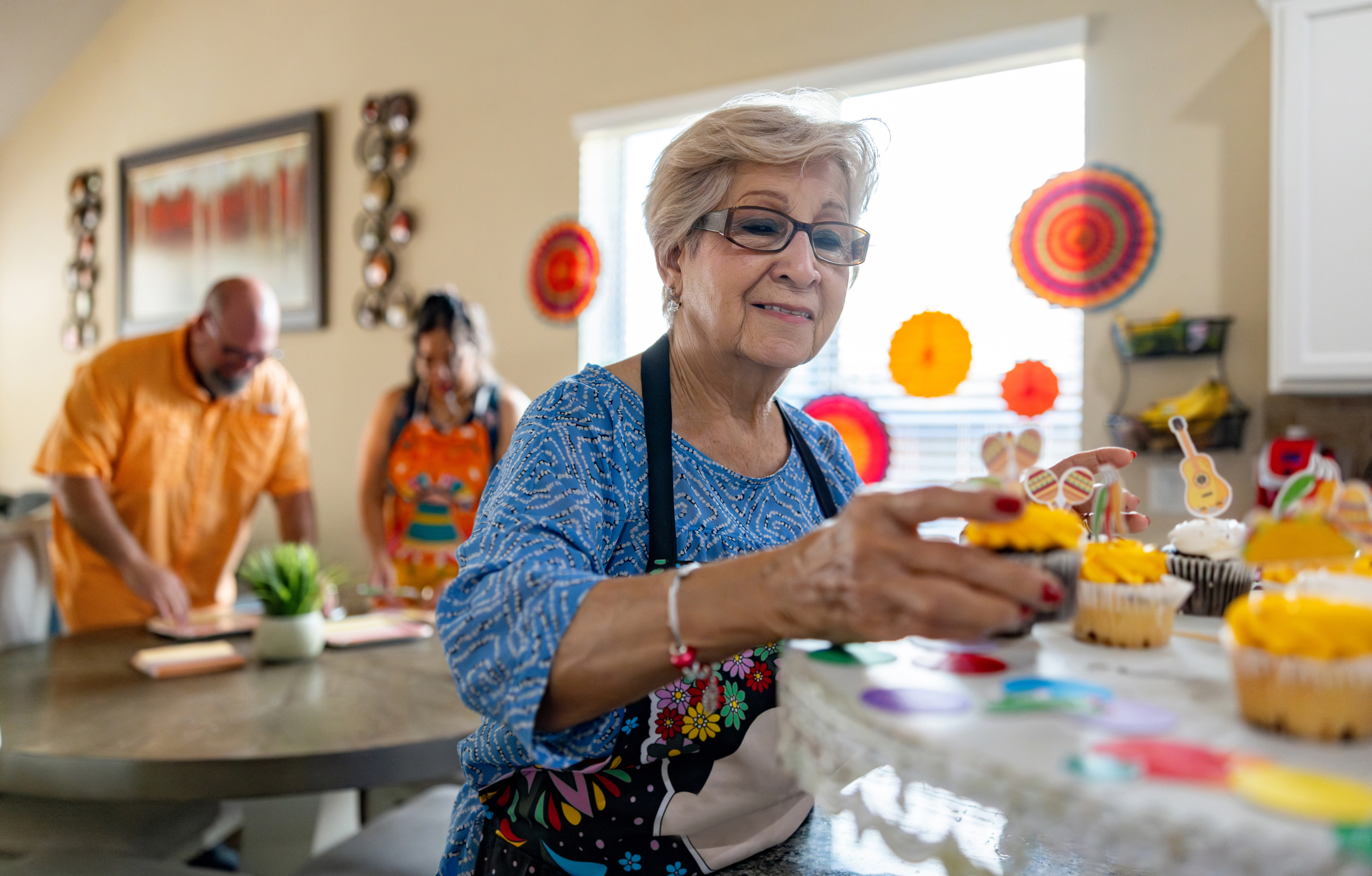 Happy senior woman making cupcakes at home for a Mexican party - lifestyle concepts